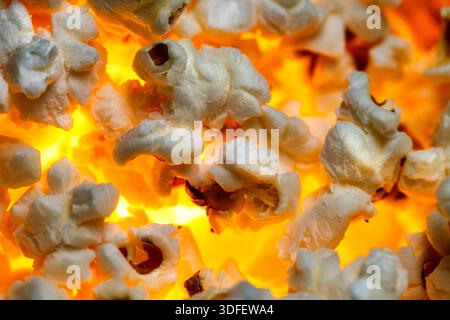 Eine Nahaufnahme von Popcorn mit einem leuchtend orangen und gelben Hintergrund. Stockfoto