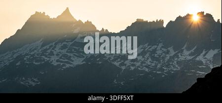Sonnenaufgang über zerklüfteten Berggipfeln mit Schneelichtern. Stockfoto