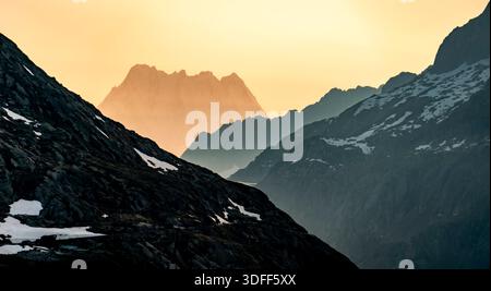 Eine ruhige Berglandschaft bei Sonnenuntergang mit Silhouettengipfeln. Stockfoto