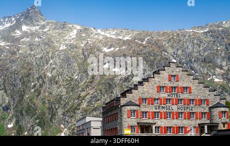 Historisches Hotel mit roten Fensterläden vor Bergkulisse. Stockfoto