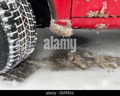 SUV-Reifen und Kotflügel bedeckt mit Schnee und Schlamm nach einer Fahrt auf einer mit Eis und Salz bedeckten Winterstraße Stockfoto