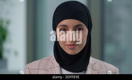 Porträt im Amt glückliche ruhige arabische ethnische muslimische Geschäftsfrau indische islamische Geschäftsfrau, die in die Kamera schaut, trägt Hijab weibliche Profi Stockfoto