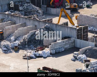 Luftaufnahme einer Altmetallrecyclinganlage mit Metallstapeln und Maschinen, die für den Recyclingprozess verwendet werden. Stockfoto