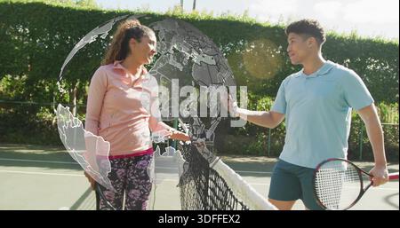 Lächelnde Tennisspieler schütteln sich die Hände in der Nähe des Netzes auf dem Platz, pinkfarbene, blaue Poloschläger Stockfoto