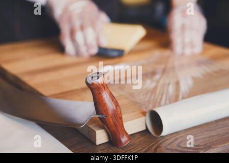 Der Ladenassistent wickelt ein Stück Käse ein Stockfoto