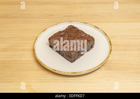Brownie mit geschmolzener Schokolade, die beim Schneiden herausströmt, serviert mit einer Schaufel Vanilleeis, das auf der warmen Oberfläche schmilzt Stockfoto