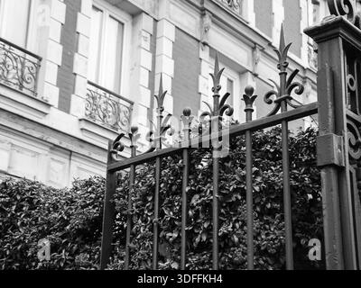 Typisches Pariser Gebäude mit Schmiedetor und farbenfrohen feuerdornbüschen. Herbst in Paris. Veraltetes Foto. Schwarz-weiß. Stockfoto