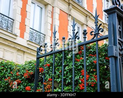 Typisches Pariser Gebäude mit Schmiedetor und farbenfrohen feuerdornbüschen. Herbst in Paris. Stockfoto