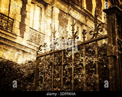 Typisches Pariser Gebäude mit Schmiedetor und farbenfrohen feuerdornbüschen. Herbst in Paris. Retro-Foto mit Kratzern. Sepia. Stockfoto
