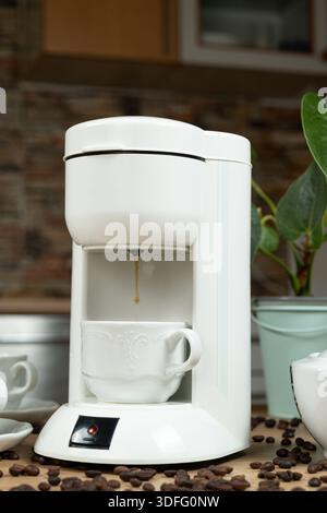 Kaffee-Brühvorgang in einer Kaffeemaschine wird heißer Kaffee in eine Tasse gegossen Stockfoto