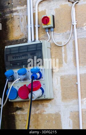 Industrielle elektrische Schalttafel und Schaltkasten, montiert an einer Außenwand mit Netzsteckdosen und Kabelkanälen Stockfoto