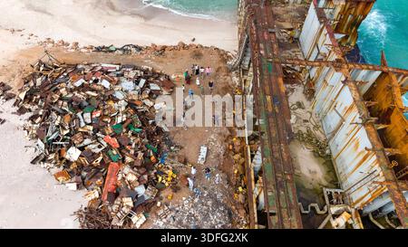 Aus der Vogelperspektive eines rostigen Schiffswracks an einem Sandstrand mit Trümmern. Sokotra, Jemen. Stockfoto
