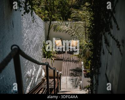 Treppe führt hinunter zu einer Terrasse Sitzbereich in einem grünen Innenhof Garten, keine Leute. Stockfoto