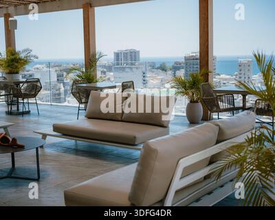 Moderne Dachterrasse mit Lounge-Möbeln im Freien mit Blick auf das Meer und die Stadt. Stockfoto