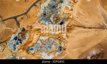 Aus der Vogelperspektive zeigt Hverir Namaskard in der Nähe des Lake Myvatn in Island mit schwefelbefleckter Erde, dampfenden Schlammtöpfen, blauen schwarzen Pools und einer Promenade dazwischen Stockfoto
