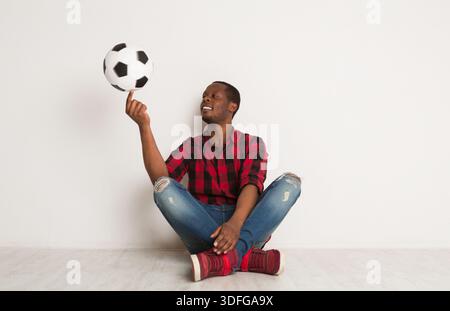 Glücklicher, lächelnder schwarzer Mann, der sich einen Ball auf dem Finger dreht Stockfoto