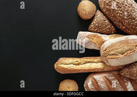 Frisch gebackenes Sortiment an handwerklich hergestellten Broten auf dunkler Oberfläche Stockfoto