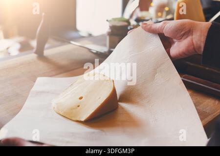 Eine Verkäuferin, die ein Stück Käse einwickelt Stockfoto