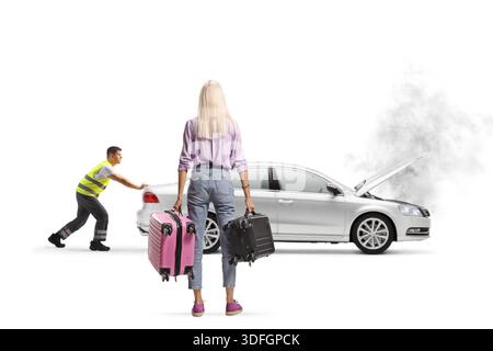 Rückansicht einer Fahrerin mit Koffern, die ihr kaputtes Auto auf weißem Hintergrund sieht Stockfoto