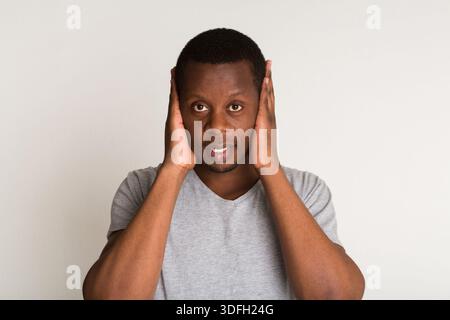 Porträt eines hübschen schwarzen Mannes, der Ohren isoliert auf weißem Hintergrund bedeckt Stockfoto