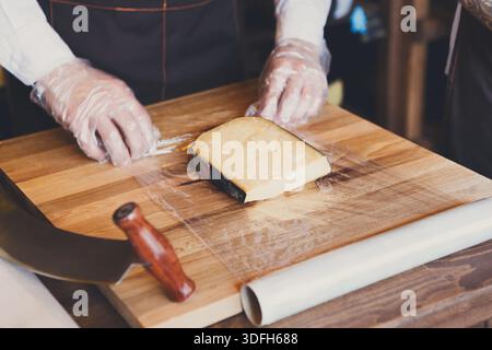 Der Ladenassistent wickelt ein Stück Käse ein Stockfoto