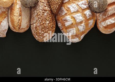 Verschiedene frische Brotsorten auf dunkler Oberfläche in einer Bäckerei Stockfoto