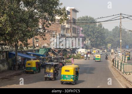 Straße mit Tuk Tuks, Fußgängern und Straßenständen in Delhi, Indien. Stockfoto