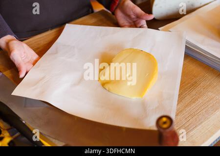 Eine Verkäuferin, die ein Stück Käse einwickelt Stockfoto