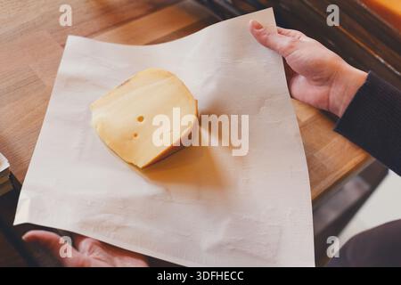 Eine Verkäuferin, die ein Stück Käse einwickelt Stockfoto
