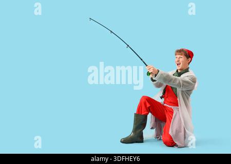 Lustiger junger Mann mit Angelrute auf blauem Hintergrund Stockfoto