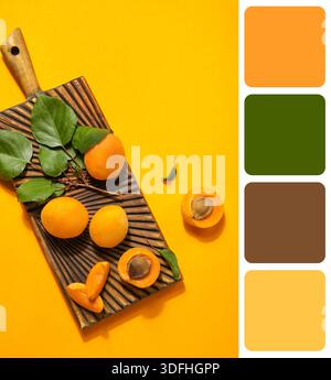 Holzbrett mit Reifen Aprikosen und grünen Blättern auf gelbem Hintergrund. Verschiedene Farbmuster Stockfoto