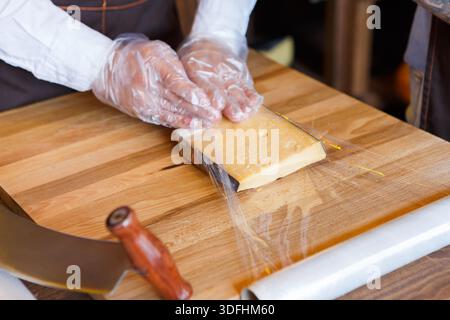 Der Ladenassistent wickelt ein Stück Käse ein Stockfoto