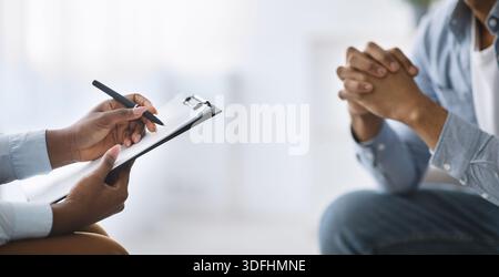 Beschnittene Ansicht eines schwarzen Mannes, der im Büro mit einem Psychotherapeuten spricht, Kopierraum. Konzept der psychischen Gesundheit Stockfoto