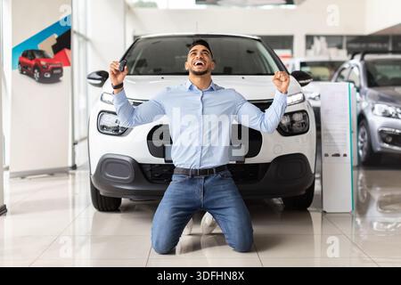 Emotionaler arabischer Kunde, der neben dem Auto kniet Stockfoto