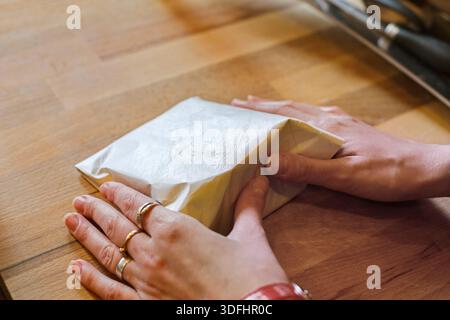 Eine Verkäuferin, die ein Stück Käse einwickelt Stockfoto