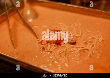 Köstliche Spaghetti mit rosafarbener Sauce und Garnelen, die warm auf einem rechteckigen Metalltablett serviert werden, sorgen beim leckeren Buffet-Abendessen für Hunger und Appetit Stockfoto