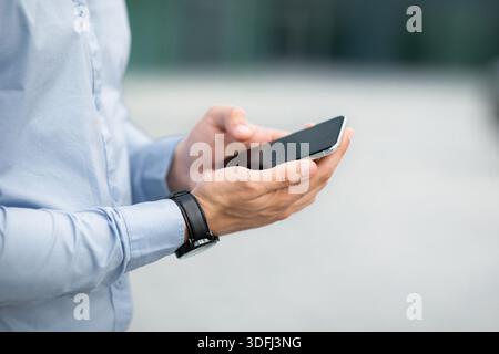 Nicht erkennbarer Geschäftsmann hält modernes Smartphone mit leerem Bildschirm, Nachbau Stockfoto