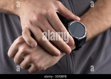Smart Watch Health Tracker mit der Herzfrequenz auf dem Bildschirm. Modernes, elegantes und innovatives tragbares Gerät. Der Athlet überprüft seine Herzfrequenz, bevor er vorzeitig ist Stockfoto
