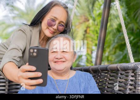 Zwei schöne lustige asiatische Frauen glückliche Mutter und Tochter machen ein gemeinsames Selfie-Foto auf dem Smartphone im Urlaub. Stockfoto