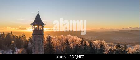 Der Stepanka-Aussichtsturm steht im Winter im Isergebirge hoch. Der Sonnenuntergang wirft ein warmes Licht über die verschneite Landschaft und zeigt die Schönheit der Natur und die friedliche Umgebung. Stockfoto