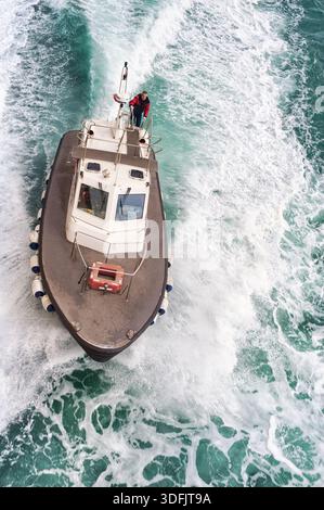 Aus der Luft blickt ein Patrouillenboot von oben nach unten, das mit hoher Geschwindigkeit durch das offene Meer navigiert und eine kraftvolle Wache hinterlässt Stockfoto