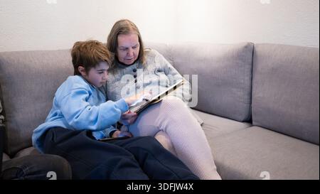 Enkel und Großmutter entspannen sich auf dem Sofa und betrachten gemeinsam einen digitalen Tablet-Bildschirm Stockfoto