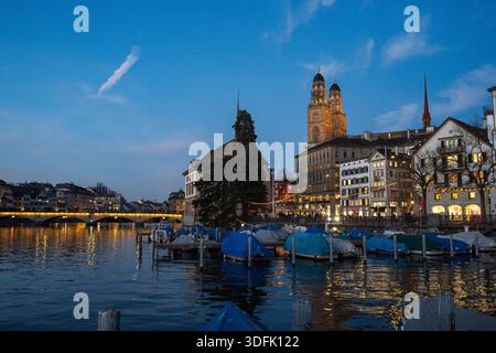 Zürich, Schweiz, 18. Dezember 2025. Altstadt mit Großmunster, Wasserkirche und Limmat in der Abenddämmerung. Weitwinkelblick, Stadtlicht, Winter e Stockfoto