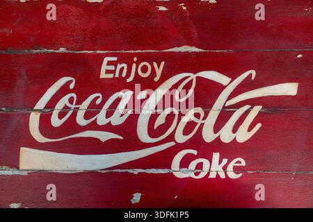 Ankara, Türkei - 5. November 2025: Vintage Coca-Cola-Logo handgemalt auf einem roten hölzernen Hintergrund, rustikales Retro Coca-Cola-Werbezeichen Stockfoto