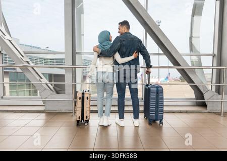 Romantische Reisen. Liebendes Muslimisches Paar, Das Mit Suitcases In Der Nähe Von Window Im Flughafen Steht Stockfoto