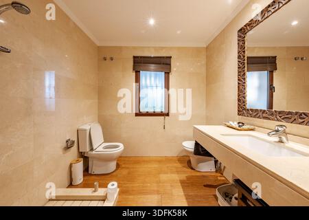 ein Bild eines kleinen Badezimmers mit Marmorwänden und Holzfußboden in mediterraner Immobilie Stockfoto