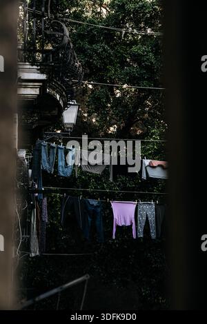 Hängewaschsalon Im Catania Courtyard Im Italienischen Stil: Bunte Kleidung Trocknet An Schlangen Zwischen Wohngebäuden In Ruhiger Alltagsszene. Stockfoto