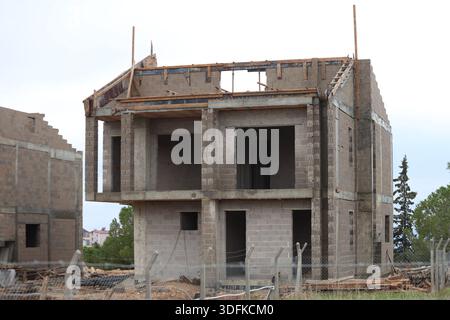 Zweistöckiges Betonblockhaus im Bau mit offenen Fensterrahmen und unvollendetem Außenmauerwerk Stockfoto