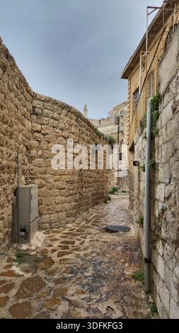 Mit Stein gepflasterte enge Straße zwischen alten Mardin Steinhäusern, Türkei Stockfoto