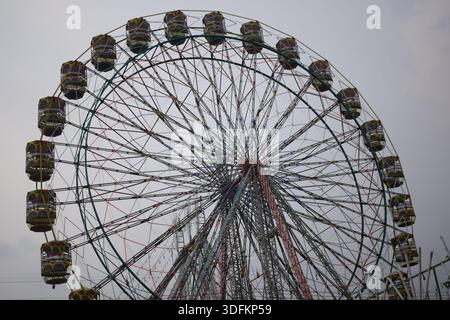 Nahaufnahme des mehrfarbigen Riesenrads während Dussehra Mela in Delhi, Indien. Unteransicht des Riesenradschwenkens. Riesenrad mit farbenfrohen Kabinen durin Stockfoto